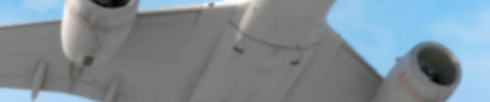 A low angle view of a plane in flight with two jet engines against a blue sky, symbolizing aviation efficiency. Soft focus.