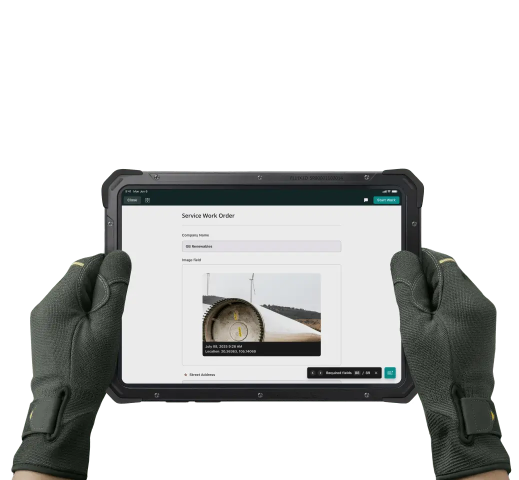 A tablet in hands with Fluix app open, showing Service Work Order form with a wind turbine photo captured with date and geolocation.