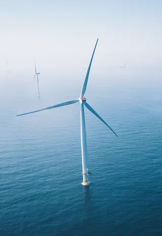 An offshore wind turbine in the open sea during fog is an example of a complex industrial infrastructure for renewable energy.