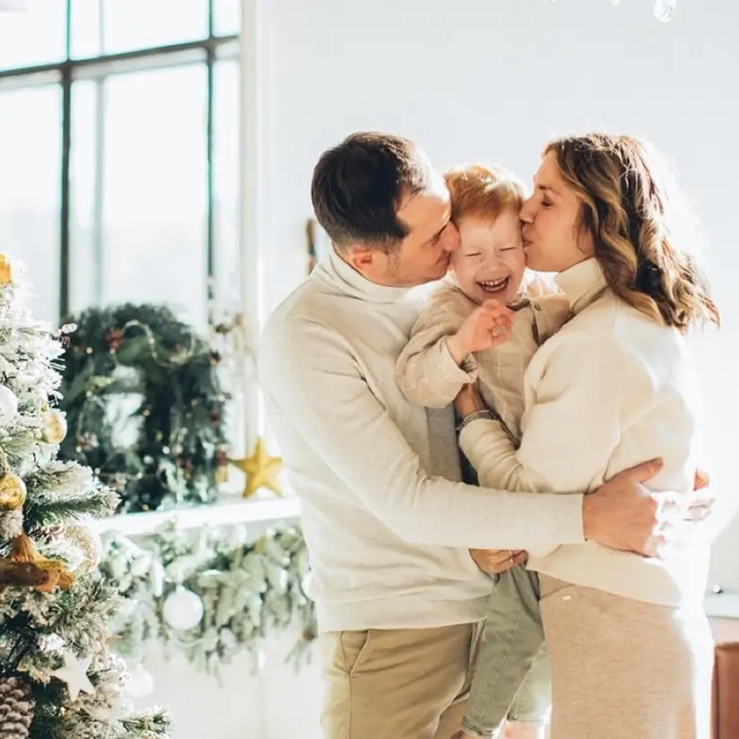The family hugs and kisses their red-haired son.
