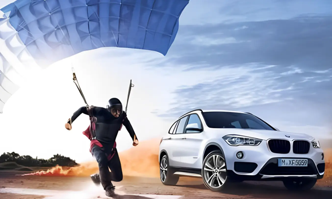 A man with a paraglider races against a BMW.