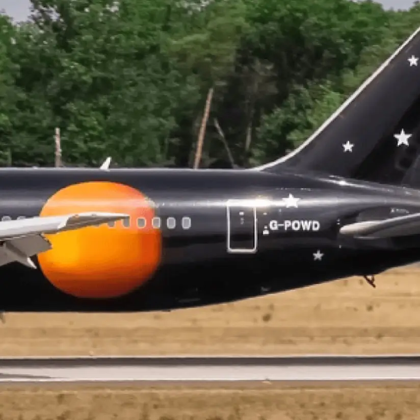 The tail of a black aircraft, featuring an image of an orange planet and stars.