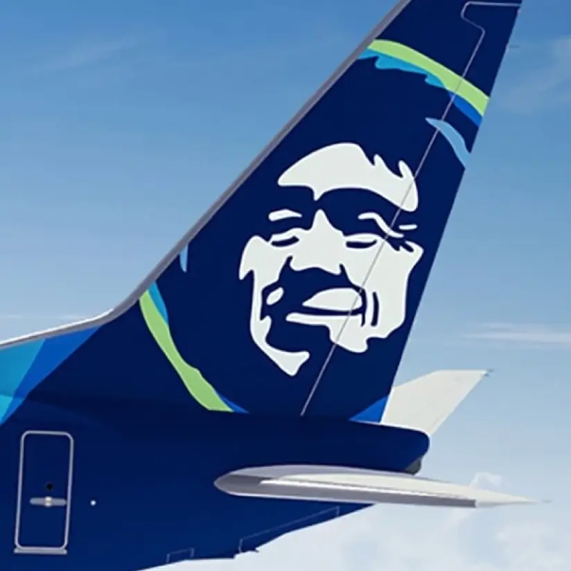 The tail of a blue airplane with a human face painted on it.