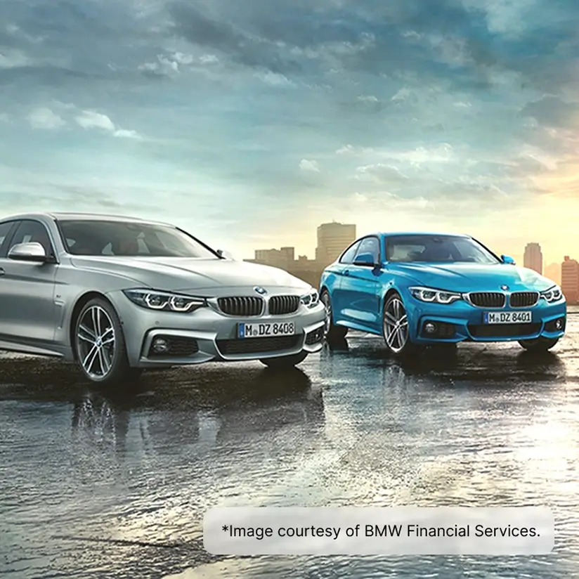 Two BMW cars on a wet surface against the backdrop of a big city.