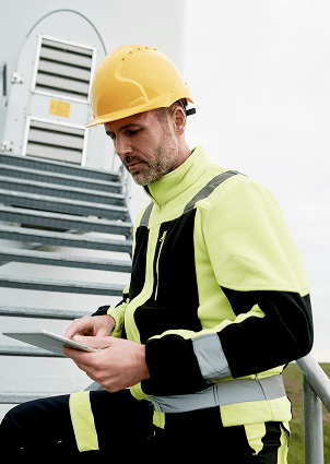 A male inspector is holding a tablet on the stairs.
