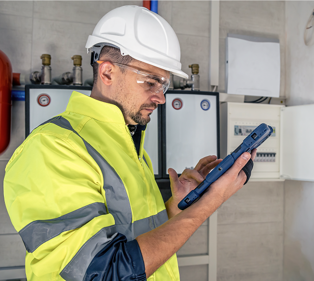 A safety inspector working with a tablet over plumbing equipment.